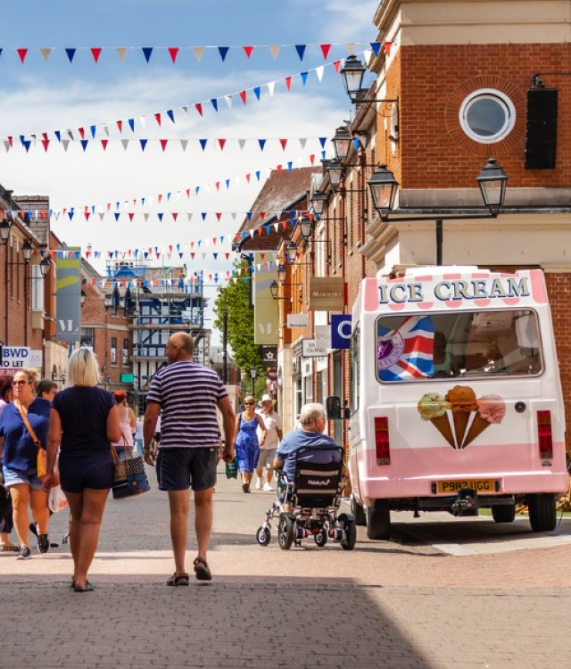Two people walk down Vicar Lane next to an ice-cream van