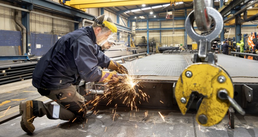 Manufacturing at Weightron. Two men working on industrial weighbridge with sparks flying