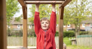 Young male pupil in red uniform on monkey bars at Heath Primary School