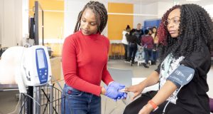 Black female student nurse practicing taking blood pressure on black female student nurse