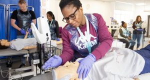 Black female in glasses practicing medicine on dummy at University of Derby, Chesterfield