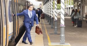 Business man in suit with briefcase stepping off train onto platform at Chesterfield Railway Station