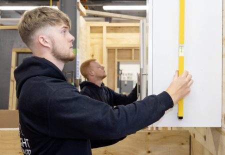 Young male measuring a cupboard door in the workshop at Chesterfield College