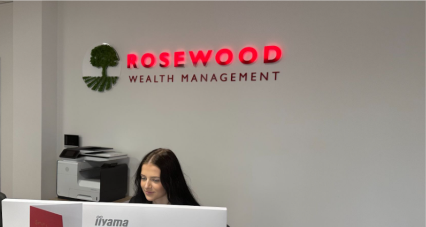 Woman sitting at a computer with the Rosewood logo behind her