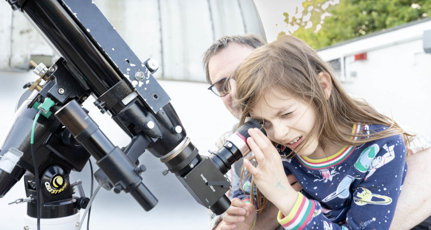 Child looking through a telescope