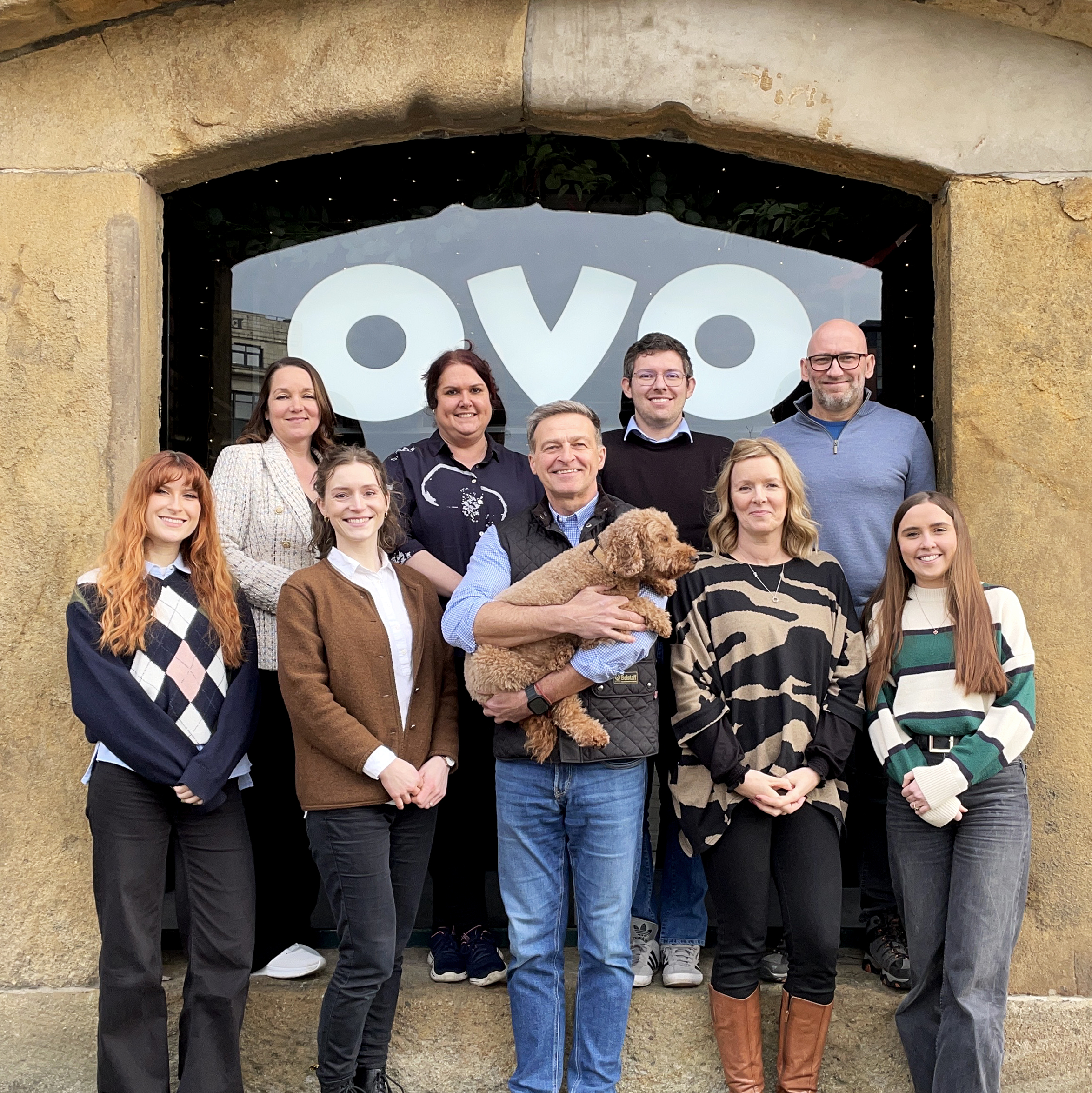 Group of 9 people and a cockapoo dog outside of ovo spaces