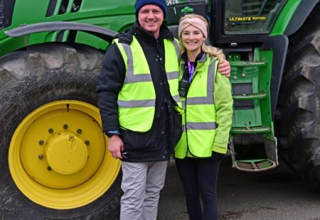 Tractor fest - Man and woman stood smiling in front of large green tractor