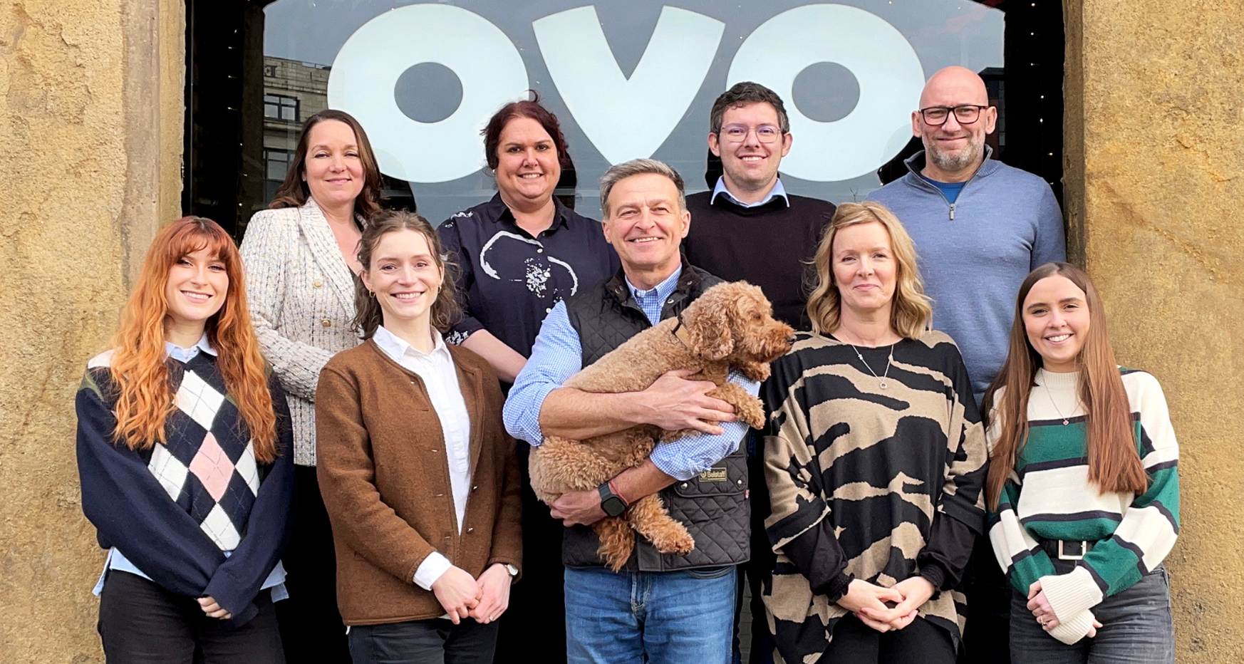 Group of 9 people and a cockapoo dog outside of ovo spaces