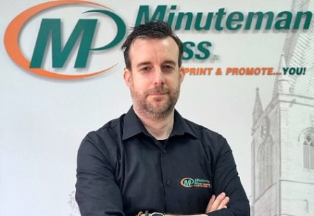 Male in black shirt in front of branded wall at Minuteman Press Chesterfield