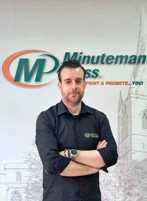 Male in black shirt in front of branded wall at Minuteman Press Chesterfield