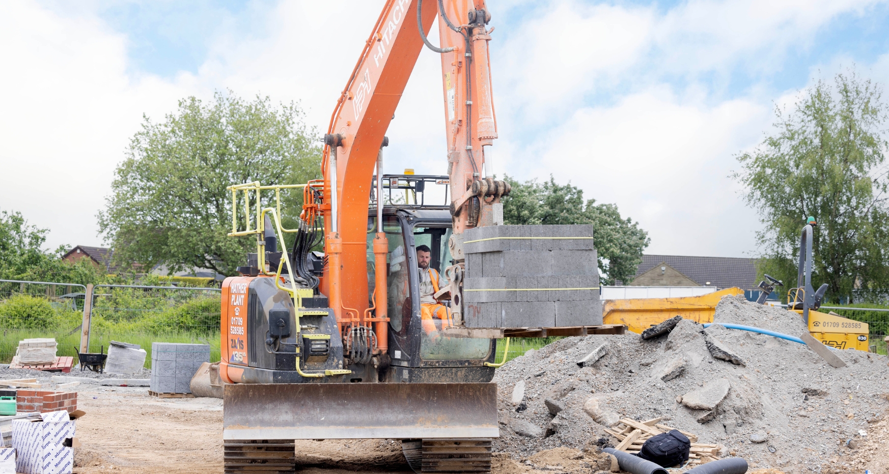 Male driving a digger, transporting concrete block