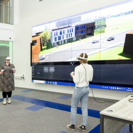 Two women wearing VR headsets and animation on big screen