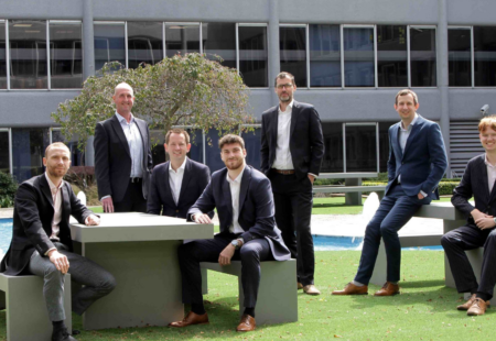 7 males in suits sat around benches in an office garden, representing the team at FHP Property Consultants