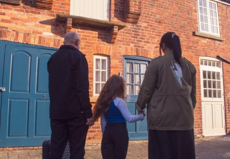 Man, girl and woman holding hands and looking at a building