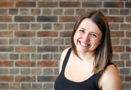 Female stood in front of brick wall smiling to the camera