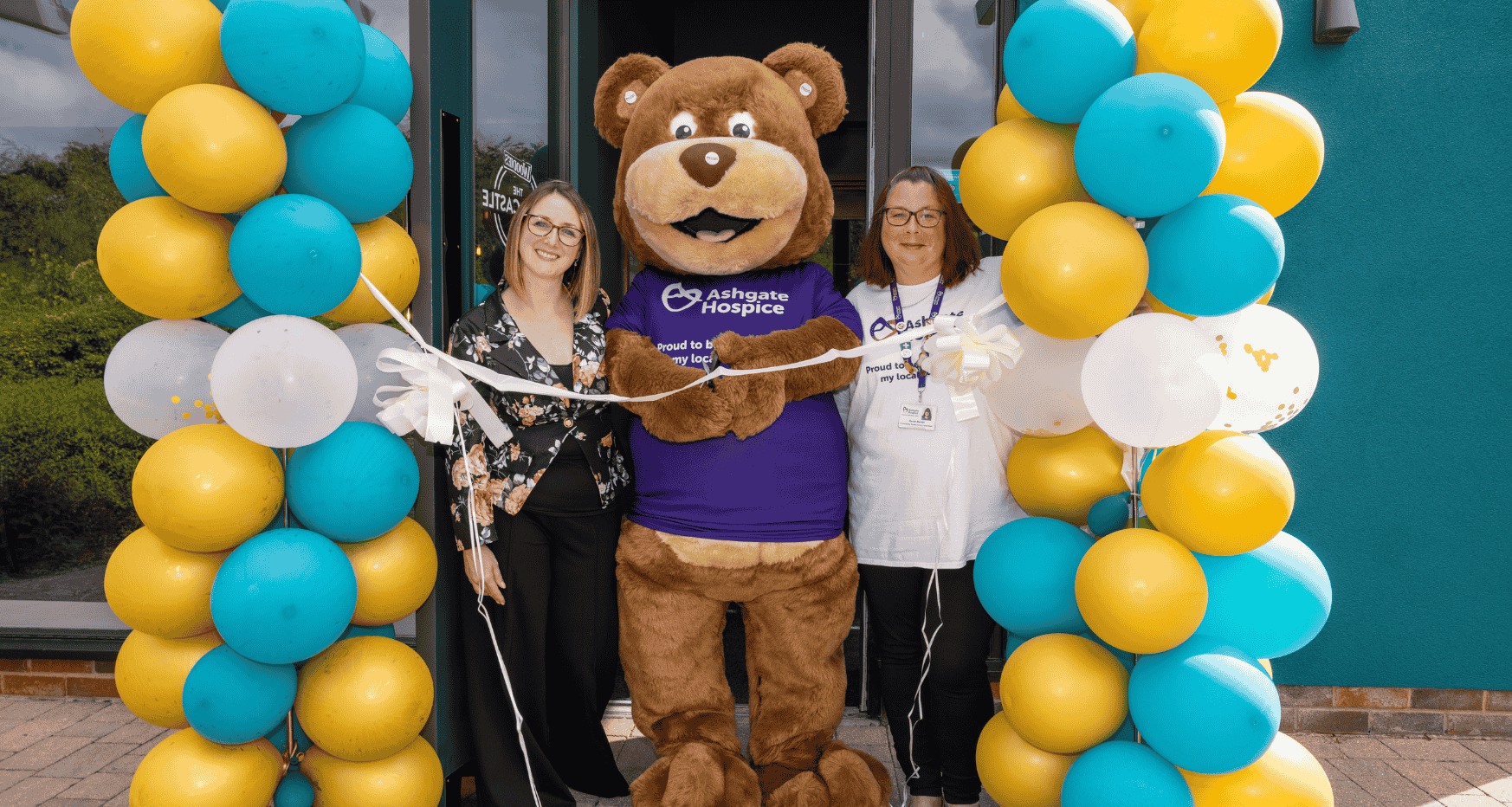 Two females with giant bear and lots of balloons at door of Woodies - former Little Castle