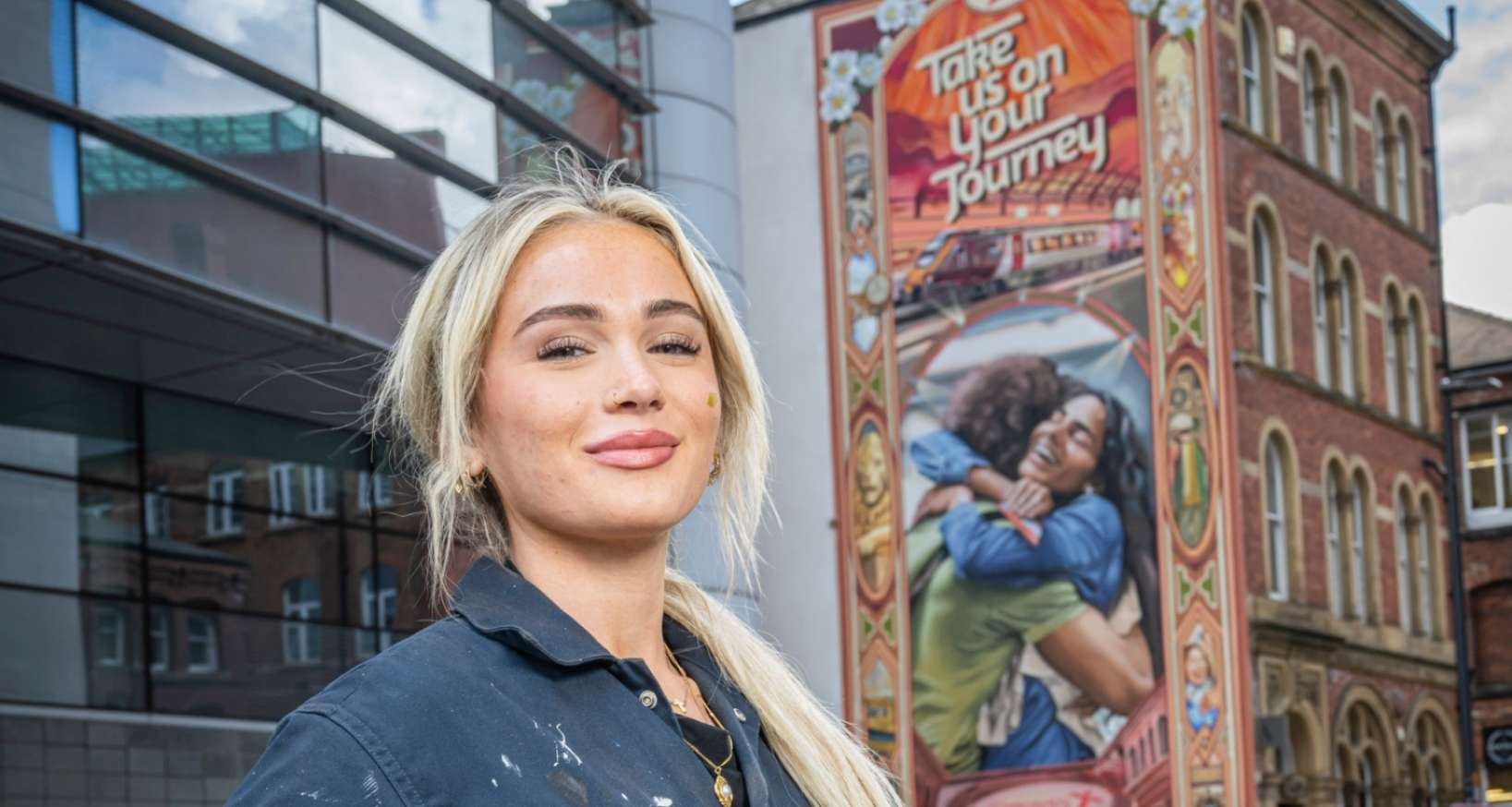 Artist Elle Koziupa stood in front of the The Embrace Mural in Leeds