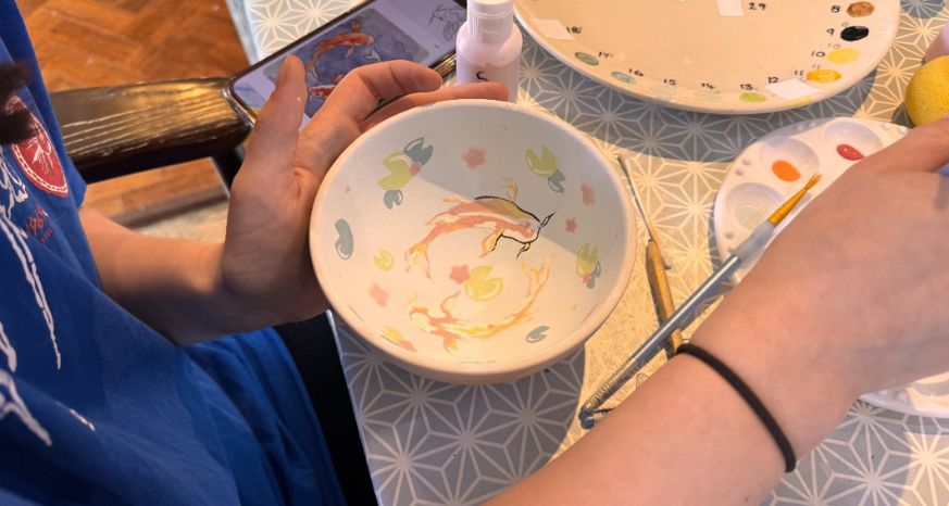 Young artist painting a bowl at Peel Pottery