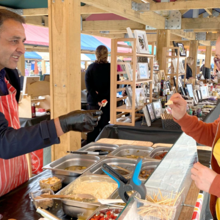 Trader giving food for customer to sample at Chesterfield Market